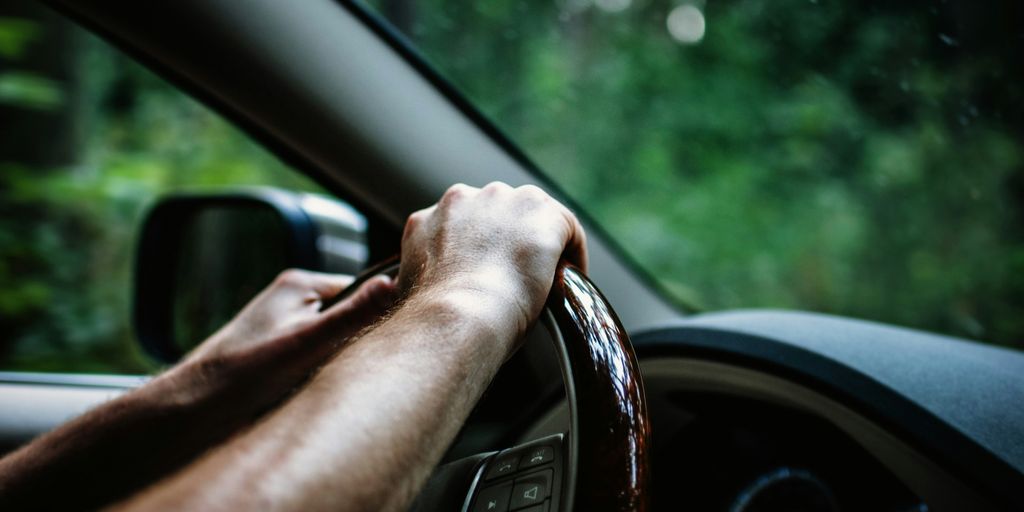 person holding car steering wheel